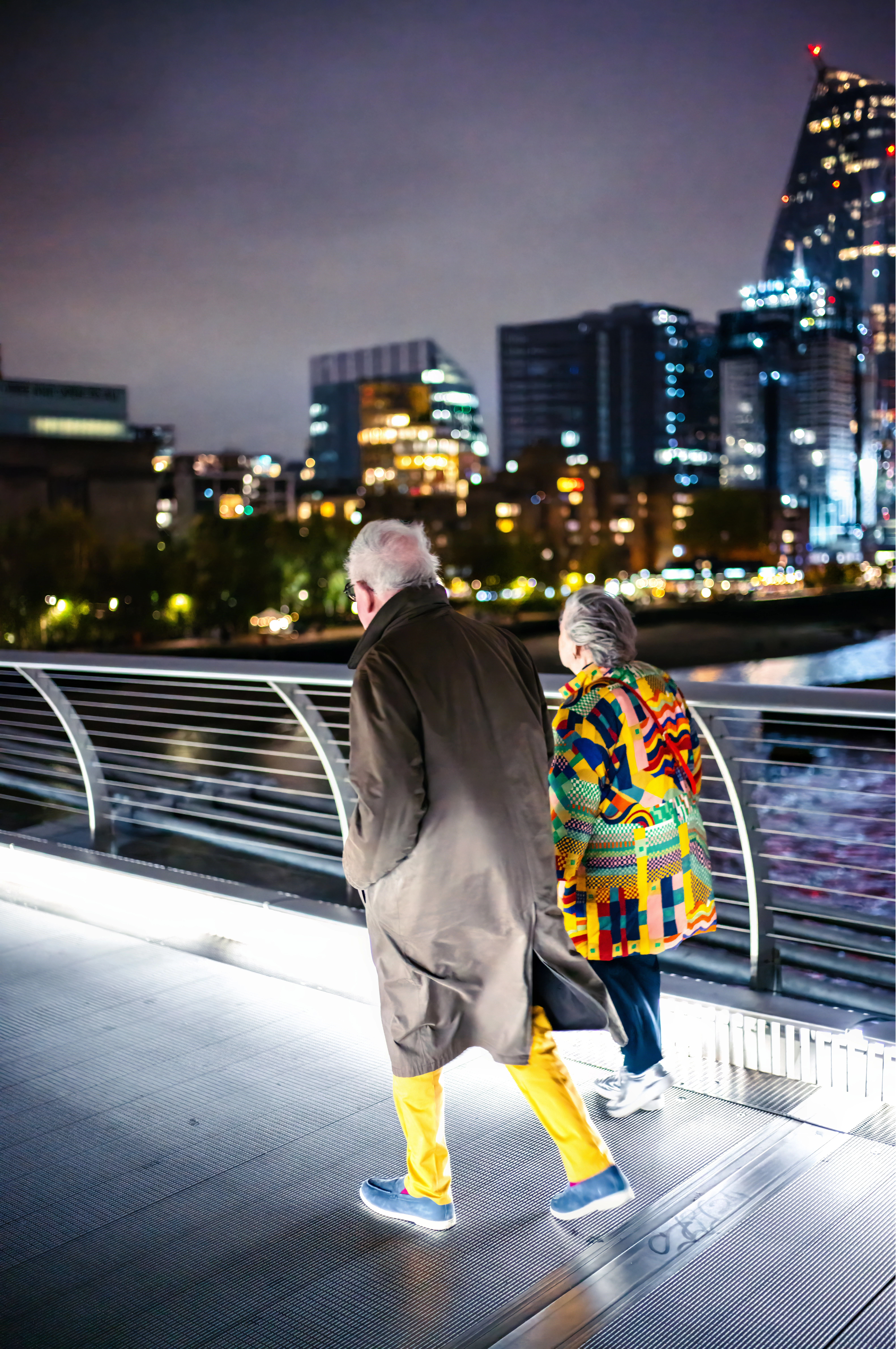 Colourful Companions Elderly couple in colourful clothing walking across Millennium Bridge at night – London street photography print